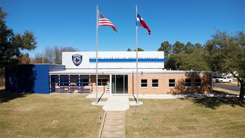 The City of Tyler Police Training Facility with the US and Texas flags flying in front under a clear blue sky.